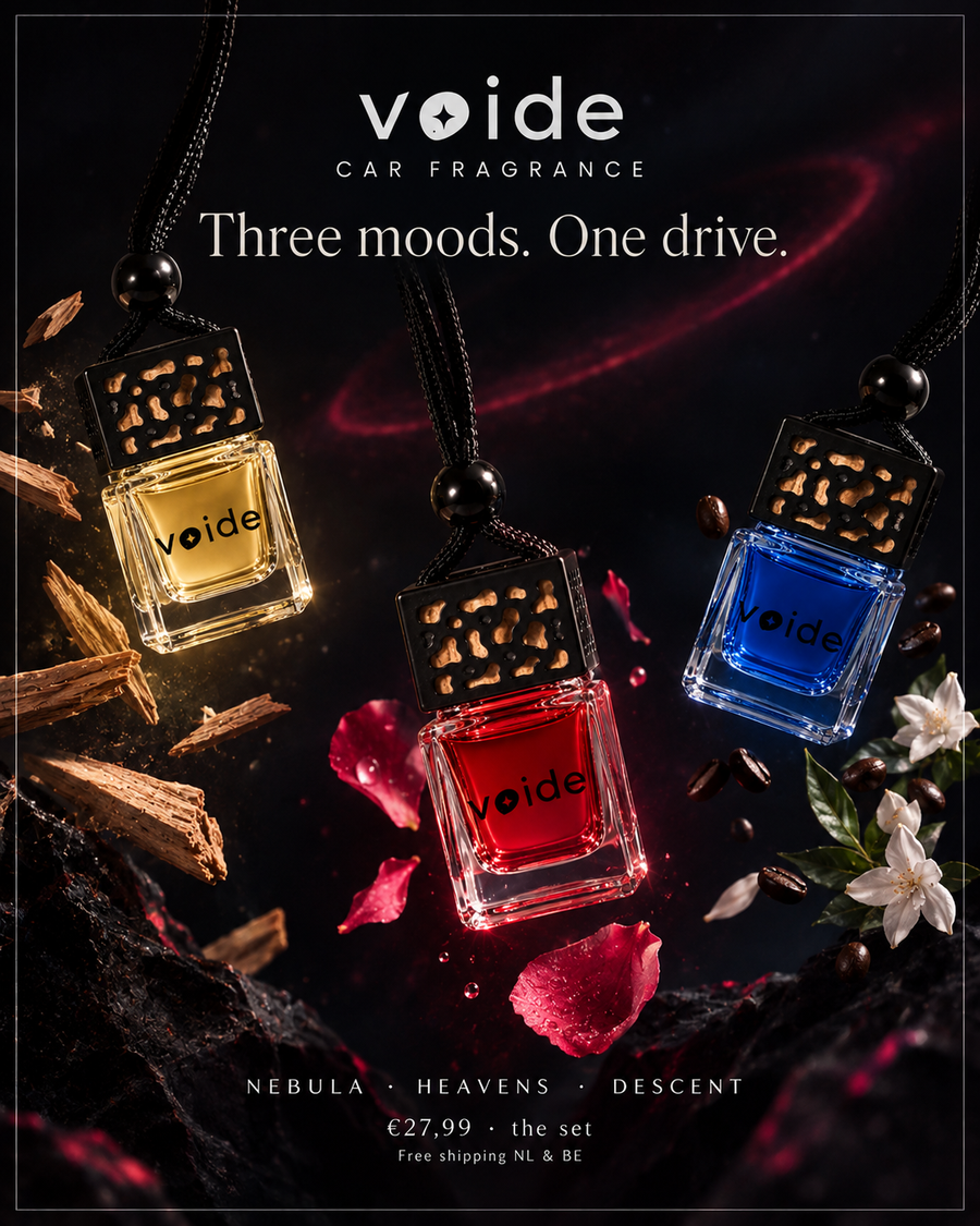 Three Voide car fragrance oil bottles with decorative black caps and black cords, shown in amber, red, and blue liquids against a dark moody background with wood chips, petals, and flowers. Text at the top reads 'voide CAR FRAGRANCE' and 'Three moods.