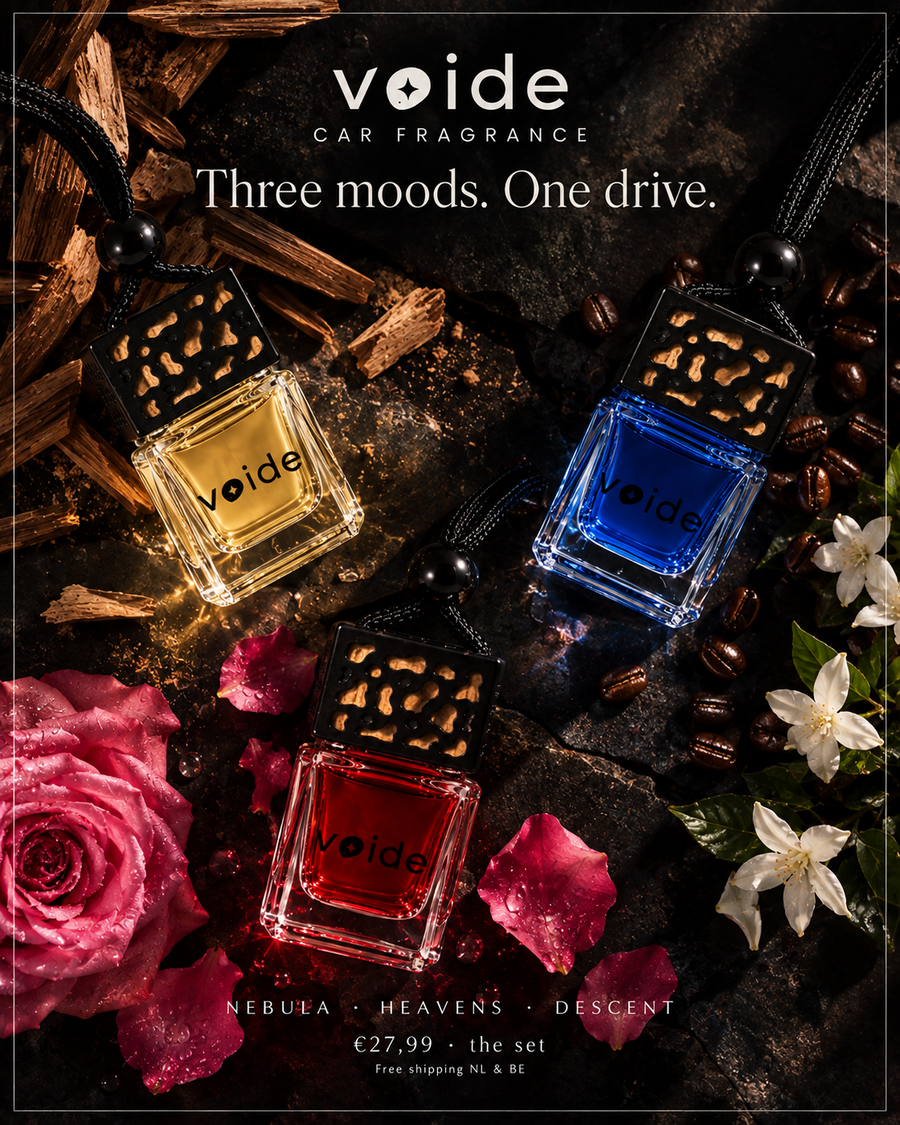 Three Voide Car Fragrance bottles in amber, blue, and red, arranged with roses, wood, and coffee beans on a dark textured background. The brand name 'voide' is displayed at the top.