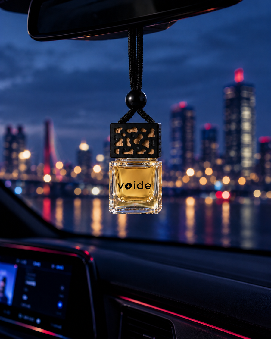 Heavens car fragrance hanging from a rear-view mirror with city lights at night
